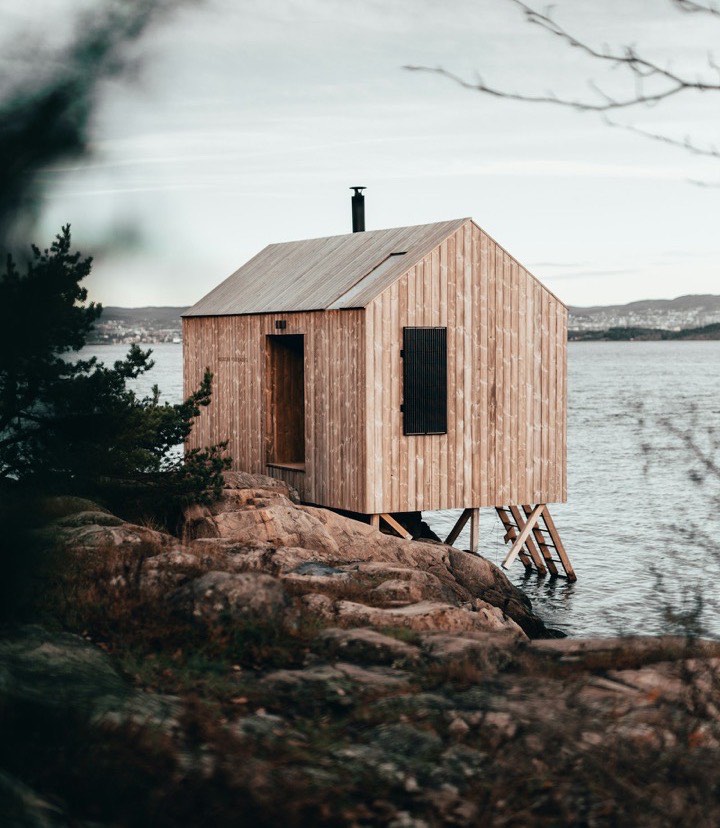 A timber-clad cabin on a rocky shoreline